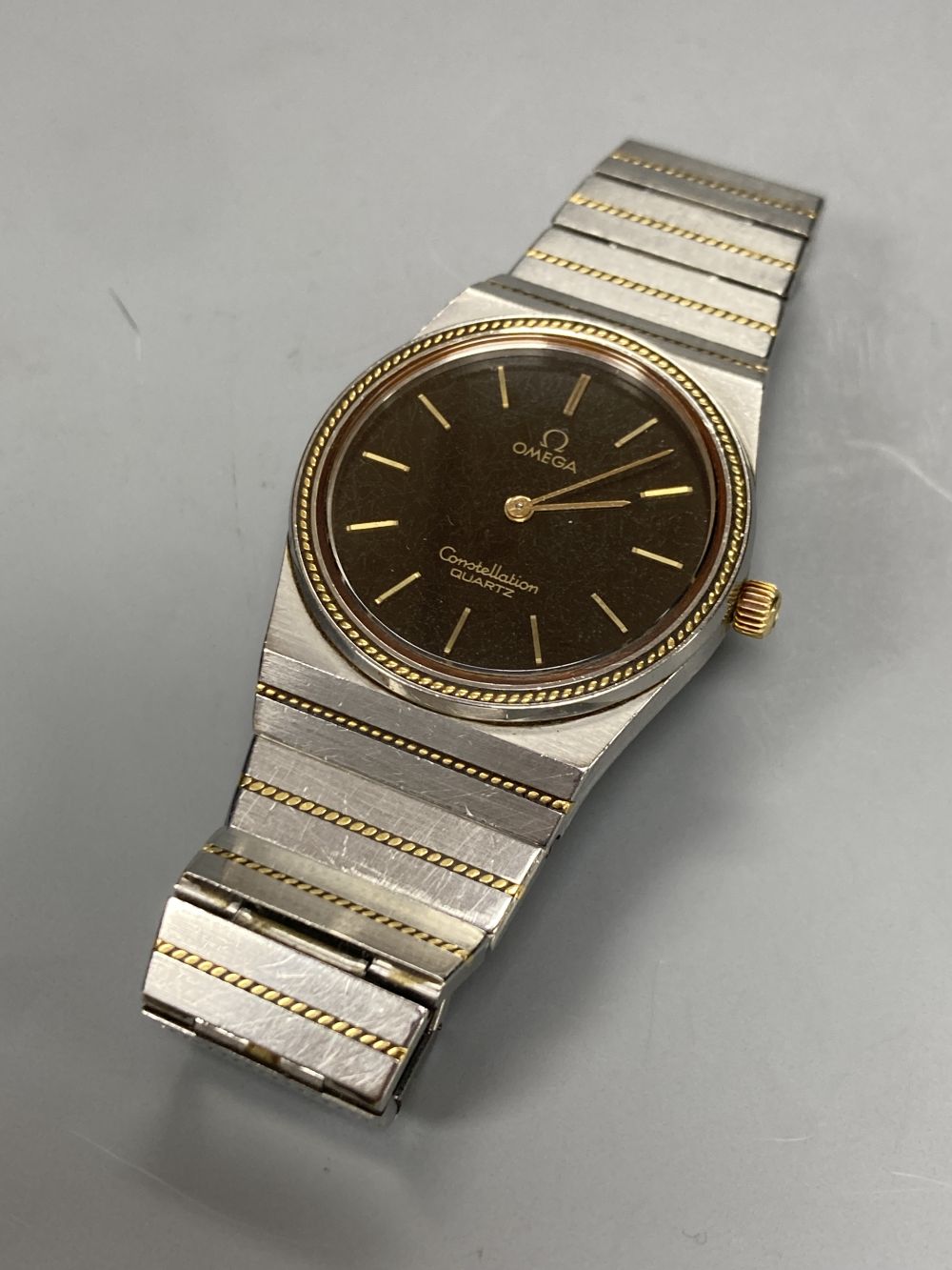 A gentlemans stainless steel and yellow metal Omega Constellation quartz wrist watch, with black dial and baton numerals,